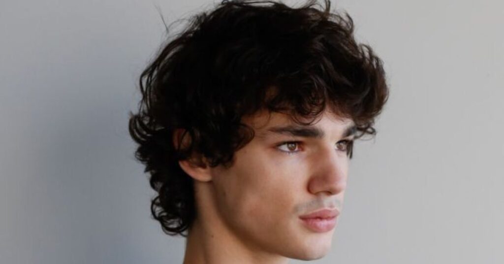 Permed mod cut with tight curls and high-volume texture.