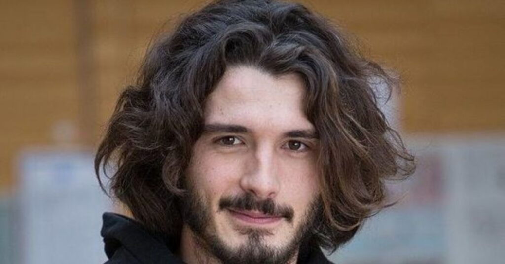 Shaggy layered bob for men with messy waves and modern nomad aesthetic