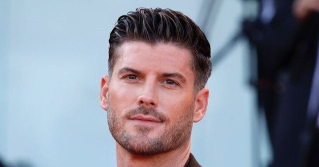 Men’s beard-balanced shag haircut featuring messy layered hair seamlessly blended into a groomed full beard with tapered sideburns.