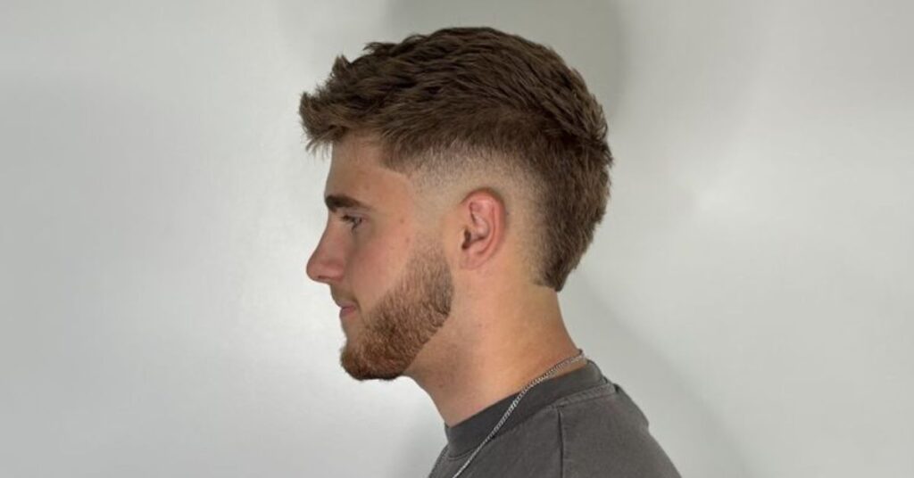 A sharp burst fade haircut that curves around the ear, leaving more length at the back of the neck.