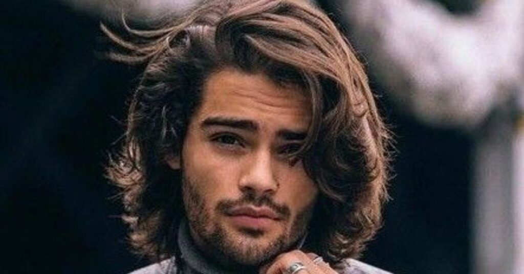 Medium-to-long layered flow hairstyle with soft waves and a relaxed look.