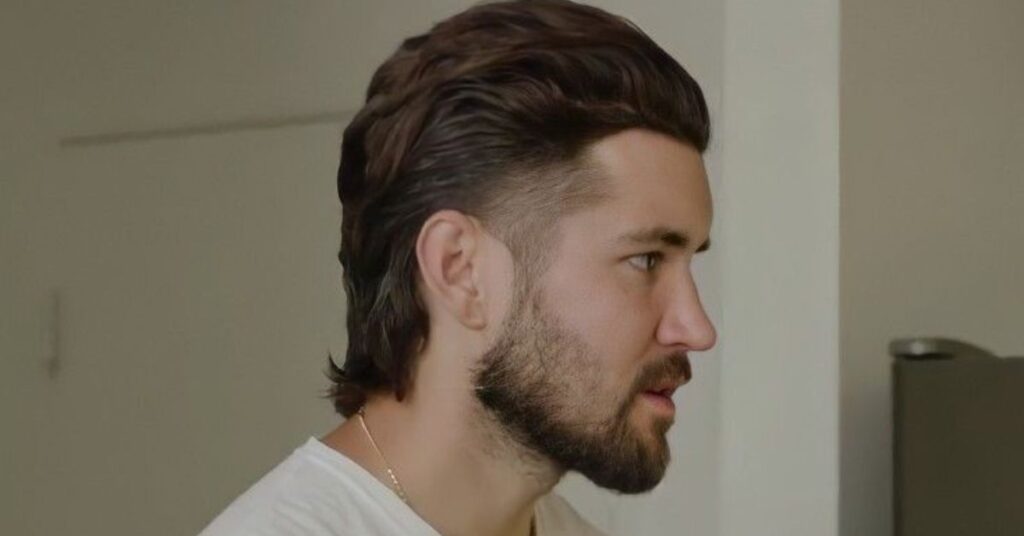 Trendy comb over mullet for men with a clean side part and long hair at the nape.