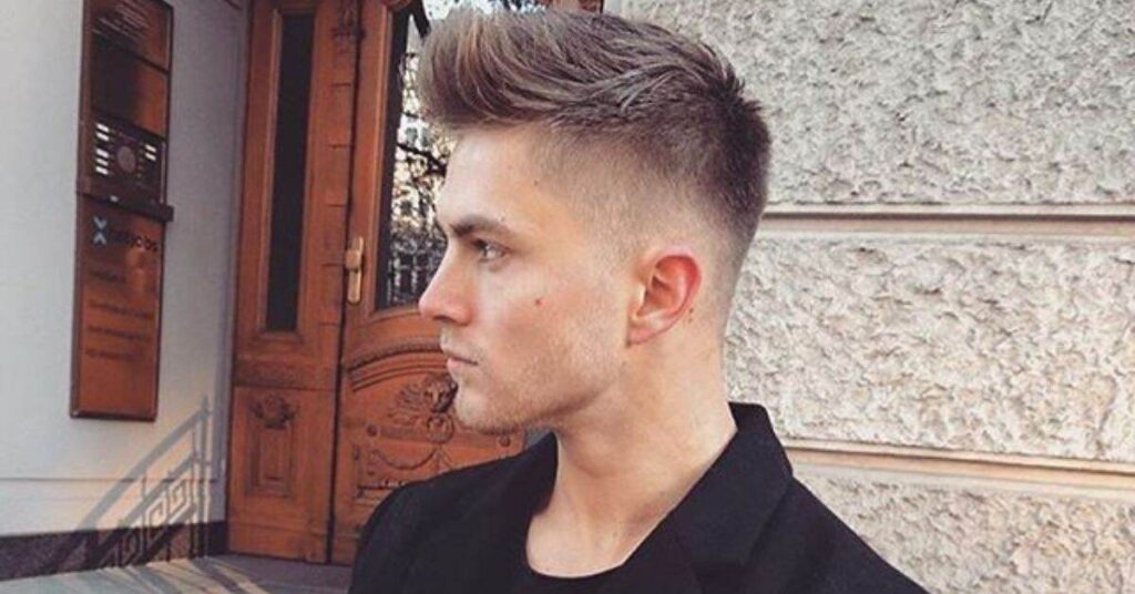 Edgy hard comb over with high fade and a deep-cut razor side part.