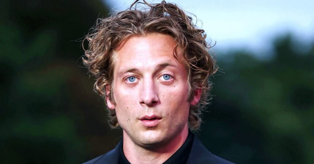 Jeremy Allen White 90s inspired middle part curly hairstyle for men.